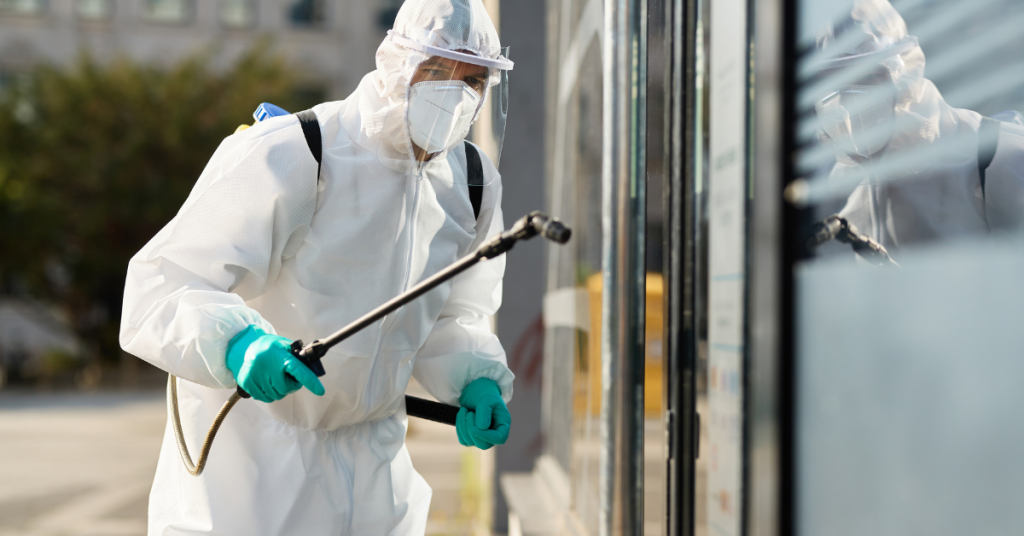 A-man-dressed-in-a-white-suit-sprays-a-house-with-pest-control-emphasizing-the-necessity-of-mosquito-management-for-home-safety.