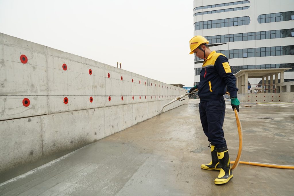 A-man-in-a-yellow-safety-suit-applies-waterproofing-concrete-spray-for-enhanced-durability-and-protection.